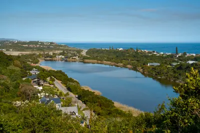 Elevated view of the Touw River Estuary at Wilderness with calm waters, coastal vegetation and the Indian Ocean beyond on South Africa's Garden Route.