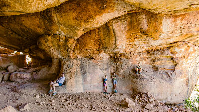 Visitors relaxing inside the vast sandstone chamber of Stadsaal Cave in the Cederberg Wilderness Area, Western Cape, South Africa.