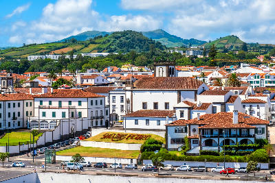 Historic buildings and the Church of São Pedro in Ponta Delgada with green hills behind the city on São Miguel Island, Azores.