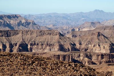 Wide view across the layered canyon escarpments and desert plateaus surrounding Fish River Canyon in southern Namibia.