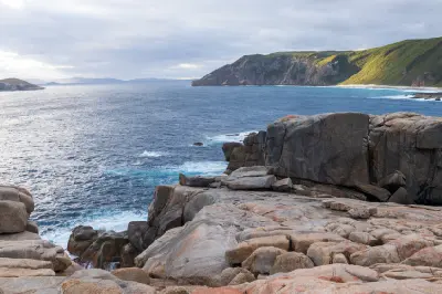 Granite coastline and ocean near Natural Bridge with green headlands in Torndirrup National Park, Western Australia.