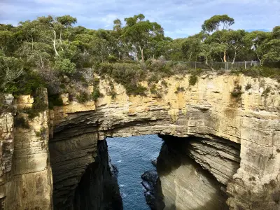 Tasman Arch forming a natural rock bridge above a narrow ocean channel on the Tasman Peninsula, Tasmania.