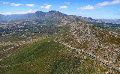 Aerial landscape of Sir Lowry’s Pass and mountain roads cutting through the Hottentots Holland Mountains near Elgin and False Bay in the Western Cape, South Africa.