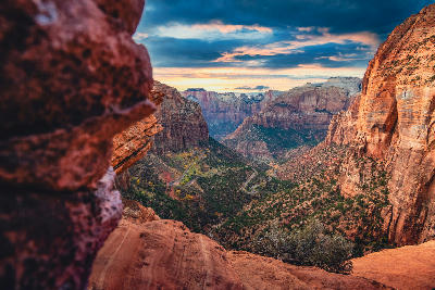 Zion Canyon viewed from Canyon Overlook Trail with winding road below and sandstone cliffs.