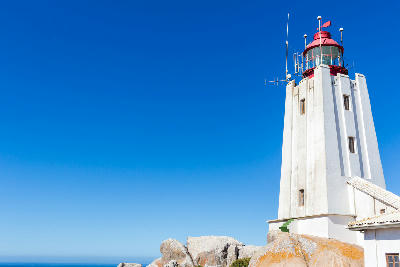 Close-up of Cape Columbine Lighthouse standing on granite rocks at Tietiesbaai near Paternoster on South Africa’s West Coast beneath a clear blue sky.