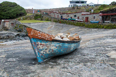 Weathered fishing boat resting beside the historic stone harbour buildings at Old Harbour Hermanus, South Africa