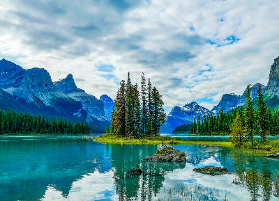 Spirit Island on Maligne Lake with turquoise water, pine trees, and mountain peaks reflected under a cloudy sky