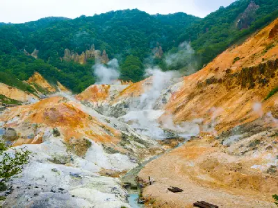 Steam rising from sulphur-coloured geothermal slopes in Jigokudani Hell Valley, Noboribetsu, Hokkaido, Japan.