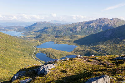 Interior Senja Norway with alpine lakes, rolling tundra landscape and distant mountain ridges viewed from elevated hillside.