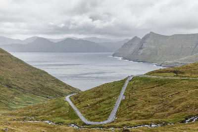 Winding mountain road leading down to Funningsfjørður fjord on Eysturoy, Faroe Islands.