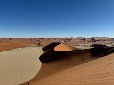 View from the top of Big Daddy Dune above the pale Deadvlei basin and red sand dunes in Namibia’s Namib Desert.