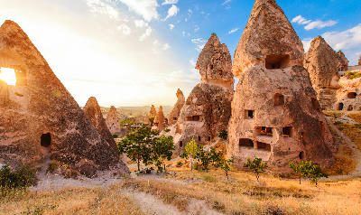 Cappadocia showing a valley landscape in the Nevşehir region at sunset, with layered rock formations and long shadows.