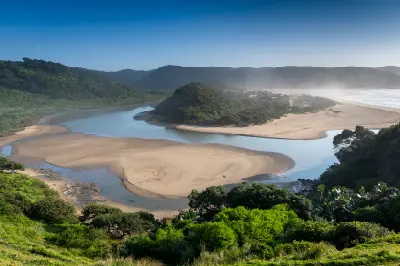 alt="Mdumbi River Mouth estuary winding through coastal forest and sandbanks before entering the Indian Ocean on the Wild Coast, Eastern Cape, South Africa."