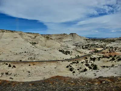 Utah Scenic Byway 12 winds through pale sandstone hills and sparse desert vegetation near the Lower Calf Creek Falls trailhead.