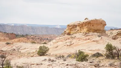 Layered sandstone formations and sparse desert vegetation across the arid landscape surrounding the Peek-a-Boo and Spooky slot canyons.