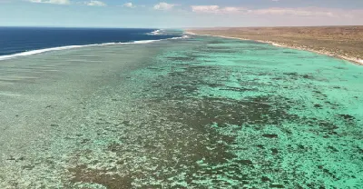 Aerial view across the vast shallow reef and turquoise lagoon of Ningaloo Reef beside the Cape Range coast.