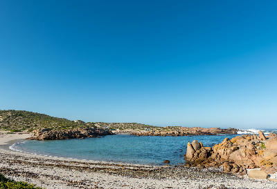 Sheltered bay at Tietiesbaai near Paternoster with granite boulders, a sandy beach, turquoise water and coastal fynbos within Cape Columbine Nature Reserve, South Africa.
