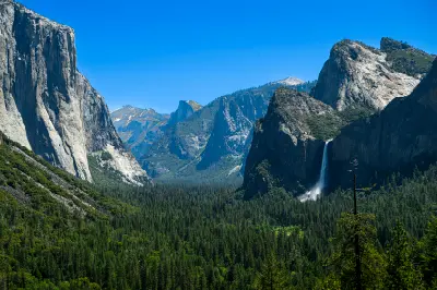 Tunnel View Yosemite Valley California showing El Capitan, Half Dome and Bridalveil Fall above forested valley under clear sky.