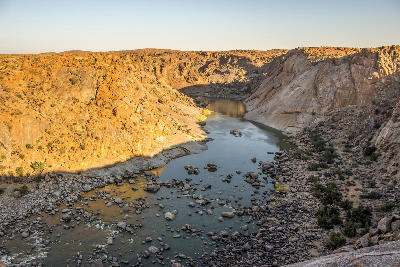 The Orange River winds between steep granite canyon walls viewed from Ararat Viewpoint in Augrabies Falls National Park, South Africa.