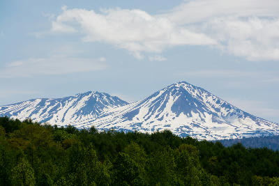 Snow-streaked slopes of Mount Asahidake rising above forested hills in Daisetsuzan National Park, Hokkaido, Japan.