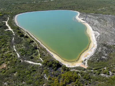 Aerial view of Lake Thetis surrounded by pale shoreline, walking paths and low coastal vegetation near Cervantes.