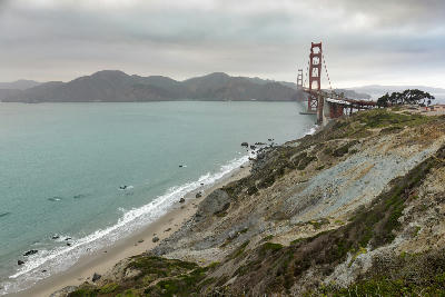 Golden Gate Bridge from Marin Headlands cliffs overlooking coastal beach and ocean in California