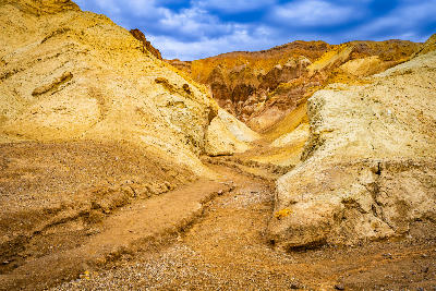 Golden Canyon trail through eroded badlands in Death Valley National Park California with layered desert rock formations and winding path