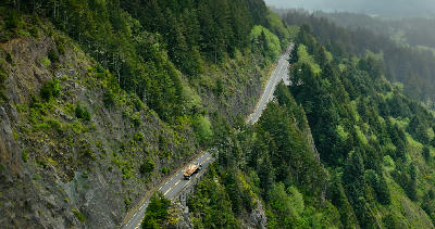 Aerial view of a coastal highway winding through forested cliffs above Neahkahnie Beach on the Oregon Coast.