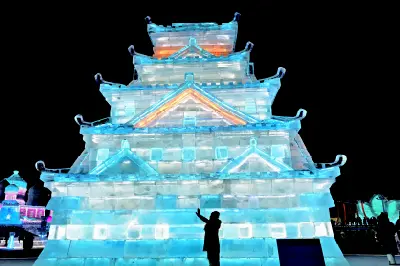 Illuminated ice castle structure at night with a person silhouette at Harbin Ice and Snow World in Harbin, China.