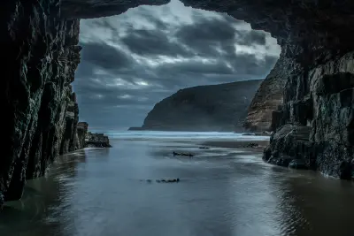 Moody coastal view framed by the rock entrance of Remarkable Cave after sunset in Tasmania.
