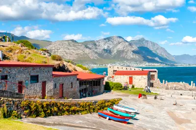 Historic stone buildings and fishing boats at Old Harbour Hermanus with mountain backdrops along the Whale Coast, South Africa