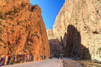 Towering canyon walls and roadside market inside Todra Gorge in Morocco