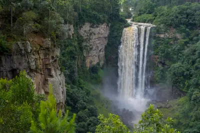 Karkloof Falls plunging into a mist-filled gorge surrounded by indigenous forest and sandstone cliffs in the KwaZulu-Natal Midlands, South Africa.