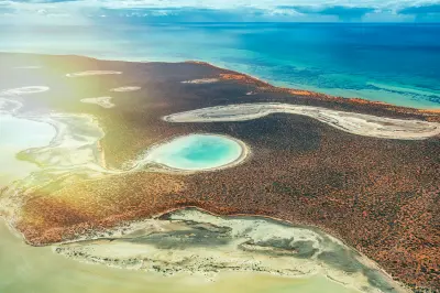 Aerial view of red coastal scrub, pale lagoons and turquoise water across Francois Peron National Park and Shark Bay.
