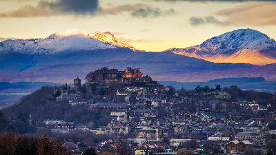 Stirling Castle rising above the city of Stirling with the surrounding hills of Central Scotland in the background.