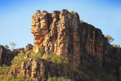 Towering weathered sandstone cliffs rise above native vegetation along the Hunter River in the Kimberley.
