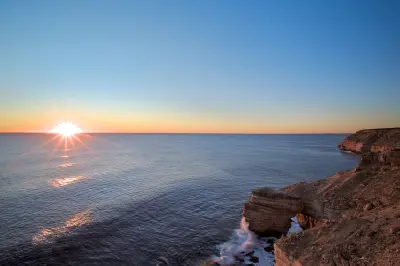 Sun setting over the Indian Ocean beside Natural Bridge on the rugged Kalbarri coast.