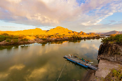 The Senderlingsdrif pontoon ferry crossing the Orange River in Richtersveld National Park, surrounded by rugged mountains and reflected evening light.