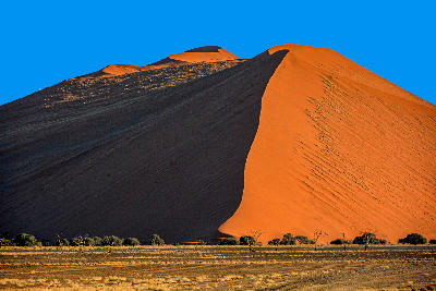 Sunlit orange face and deep shadowed slope of Dune 45 in the Sossusvlei region of Namibia.