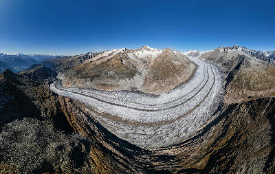 Aerial view of the Great Aletsch Glacier curving through rugged alpine ridges in the Swiss Alps.