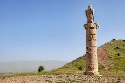 Ancient eagle-topped stone column beside the grassy Karakuş Tumulus near Kahta in Adıyaman, Turkey.