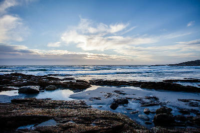 Rocky shoreline, tidal pools and Atlantic waves at sunset near Groenriviersmond in Namaqua National Park, Northern Cape, South Africa.