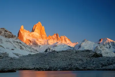 Mount Fitz Roy glowing orange at sunrise from Laguna Capri in Patagonia, Argentina.