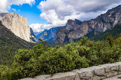 Glacier Point view in Yosemite National Park showing El Capitan, Bridalveil Fall, and granite cliffs across Yosemite Valley under dramatic clouds.