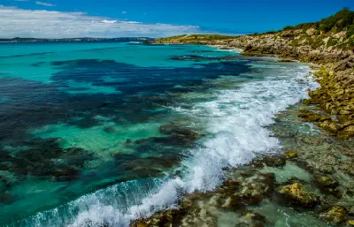 Turquoise waves breaking over shallow rock shelves and dark underwater reefs along the rocky coastline of Vivonne Bay, Kangaroo Island.