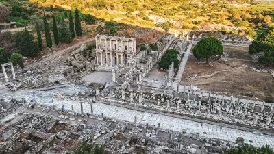 Wide aerial view of Ephesus showing the Library of Celsus, marble-paved streets, rows of columns and extensive archaeological ruins.