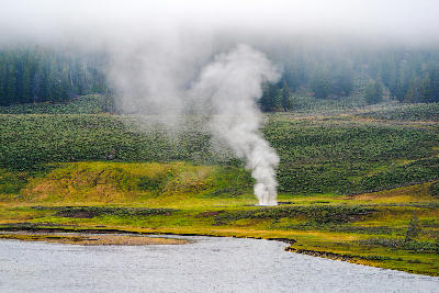 Small geyser steaming beside river Yellowstone