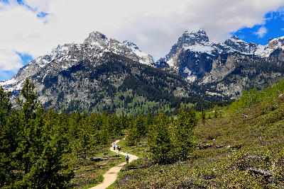 Hiking trail with people walking toward the Grand Teton Range peaks in Grand Teton National Park, Wyoming.