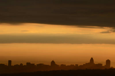 Silhouette of the Sandton skyline at sunset, with landmark office towers beneath layered clouds and a golden evening sky.