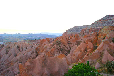Sunset over Red Valley in Cappadocia, Turkey, with colourful volcanic ridges, layered cliffs, and eroded rock formations glowing in warm evening light.